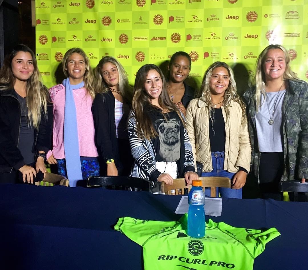 Marina Rezende with other professional surfers at a WSL event in Buenos Aires, Argentina, with a Rip Curl Pro jersey on the table.