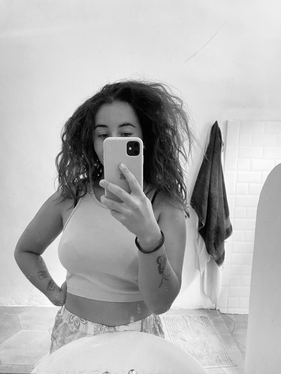 Black-and-white mirror selfie of Marina Rezende in a bathroom, her curly hair big and frizzy after the sea.