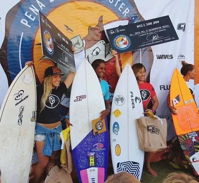Surfers on a competition podium holding prize cheques and surfboards